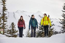 Zwei Männer und eine Frau wandern auf dem verschneiten Weg im Gebiet Klewenalp-Stockhütte.